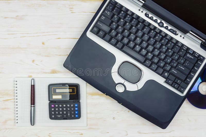 Παλαιό lap-top με έναν δίσκο λέιζερ, έναν υπολογιστή, ένα σημειωματάριο και μια μάνδρα στο α στοκ εικόνα με δικαίωμα ελεύθερης χρήσης Παλαιό lap-top με έναν δίσκο λέιζερ, έναν υπολογιστή, ένα σημειωματάριο και μια μάνδρα στο α στοκ εικόνα με δικαίωμα ελεύθερης χρήσης