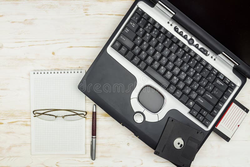 Παλαιό lap-top με τις δισκέτες, ένα σημειωματάριο, τα γυαλιά και μια μάνδρα στο α στοκ φωτογραφία με δικαίωμα ελεύθερης χρήσης Παλαιό lap-top με τις δισκέτες, ένα σημειωματάριο, τα γυαλιά και μια μάνδρα στο α στοκ φωτογραφία με δικαίωμα ελεύθερης χρήσης