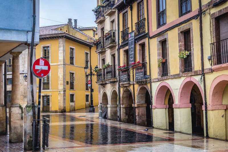 Oviedo, Spain - January 24, 2019: Historic part of Oviedo city, view from Los Zapatos street, arco, de, asturias, calle, kingdom, principality, spanish, alley, apartment, apartments, arcade, architecture, autonomous, community, building, buildings, gallery, historical, house, houses, north, northern, old, quarters, town, residential, tenement, tenements, townhouse, townhouses, yellow. Oviedo, Spain - January 24, 2019: Historic part of Oviedo city, view from Los Zapatos street, arco, de, asturias, calle, kingdom, principality, spanish, alley, apartment, apartments, arcade, architecture, autonomous, community, building, buildings, gallery, historical, house, houses, north, northern, old, quarters, town, residential, tenement, tenements, townhouse, townhouses, yellow