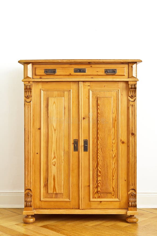 Restored vintage wooden cabinet or cupboard against the white wall of an old building with parquet flooring and stucco plastering, copy space. Restored vintage wooden cabinet or cupboard against the white wall of an old building with parquet flooring and stucco plastering, copy space.