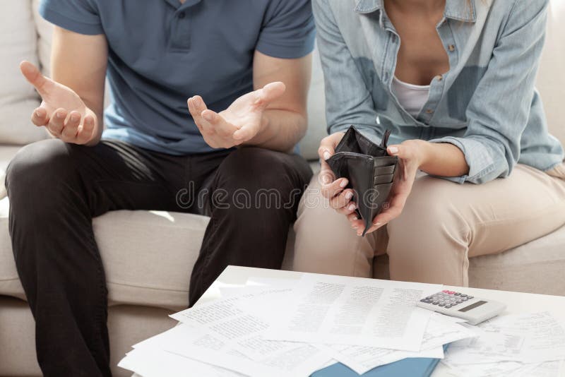 Παντρεμένο ζευγάρι που κάθεται στο σαλόνι με άδειο τοίχο και γεμάτο λογαριασμούς στοκ φωτογραφίες με δικαίωμα ελεύθερης χρήσης
