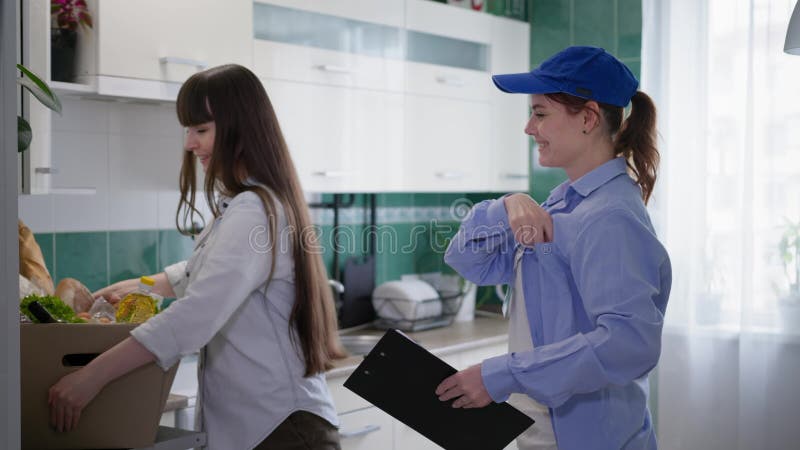 παράδοση φαγητού, όμορφη κοπέλα που εργάζεται ως ταχυδρόμος, παραδίδει ψώνια από ένα διαδικτυακό κατάστημα σε ευτυχισμένες γυναίκε φιλμ μικρού μήκους