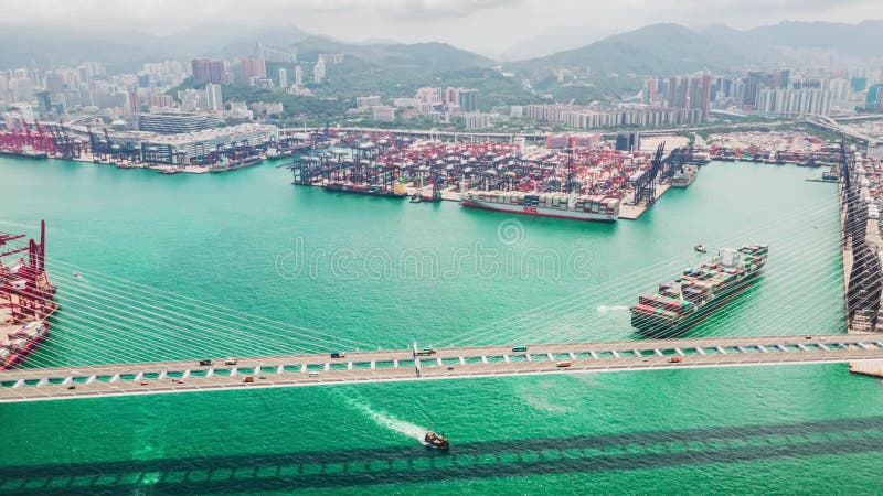 Παρέλευση του χρόνου υπερβολής της γέφυρας Stonecutters και του λιμένα του Χονγκ Κονγκ με φορτηγά πλοία, γερανούς και κυκλοφορία
