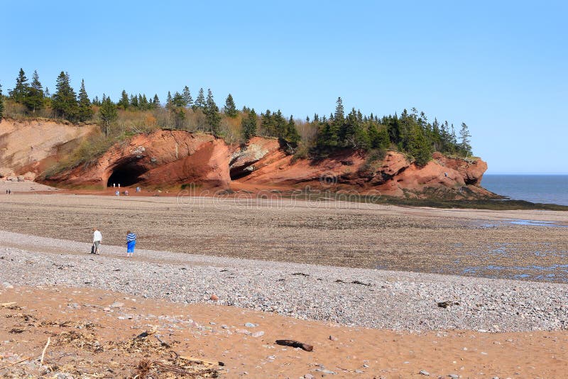 Unidentified people enjoying the rocky beach and caves at low tide in St. Martins, New Brunswick, in the Maritime Provinces of Canada. Unidentified people enjoying the rocky beach and caves at low tide in St. Martins, New Brunswick, in the Maritime Provinces of Canada