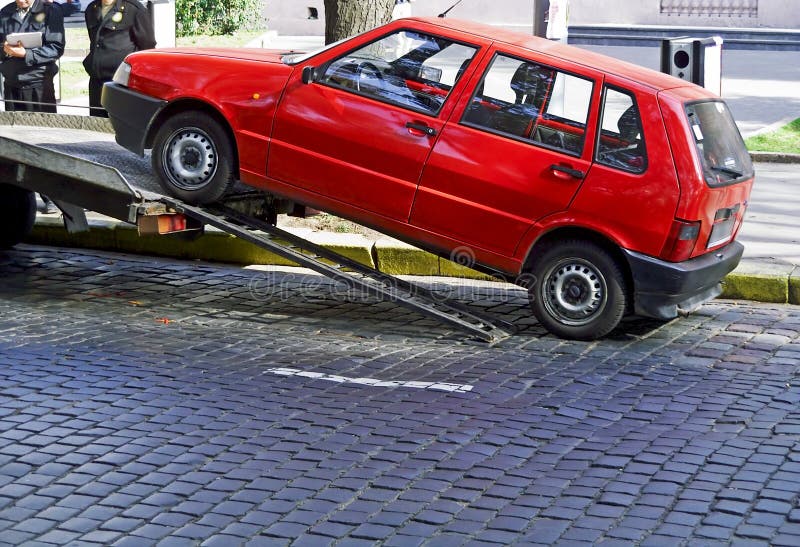 Red car towed because of parking violation. Red car towed because of parking violation