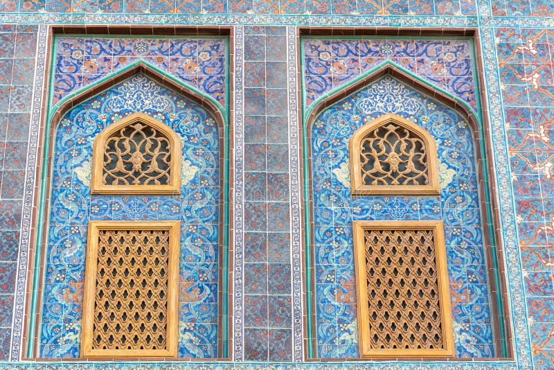 Traditional Arabic mashrabiya window on a tiled wall enclosed with carved wood latticework in Qatar. Traditional Arabic mashrabiya window on a tiled wall enclosed with carved wood latticework in Qatar