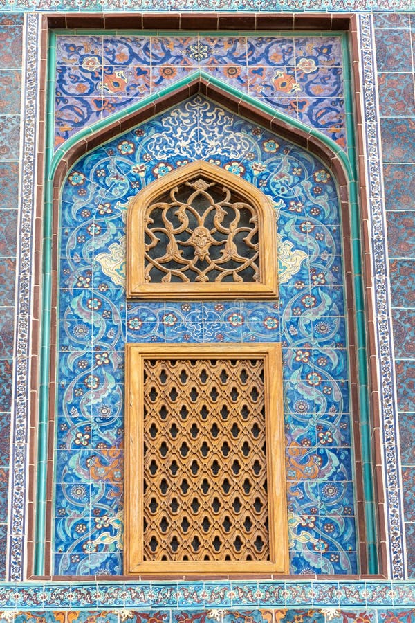 Traditional Arabic mashrabiya window on a tiled wall enclosed with carved wood latticework in Qatar. Traditional Arabic mashrabiya window on a tiled wall enclosed with carved wood latticework in Qatar