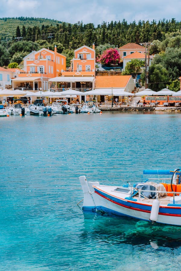Παραδοσιακό ζωηρόχρωμο ελληνικό αλιευτικό σκάφος μπροστά από το γραφικό χωριό, Ελλάδα στοκ φωτογραφία με δικαίωμα ελεύθερης χρήσης