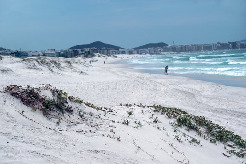 παραλία της praia das dunas με τις όμορφες θαλάσσιες λευκές αμμώδεις θίνες και την πόλη στο φόντο. στοκ εικόνα