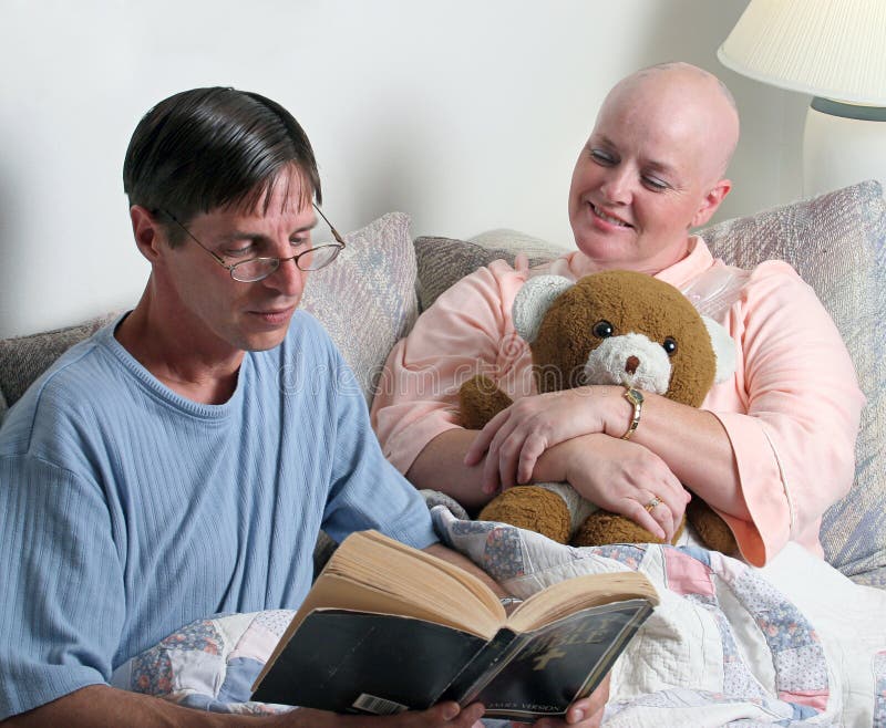 A man volunteering to read the bible to a cancer patient. (focus is on the woman's face). A man volunteering to read the bible to a cancer patient. (focus is on the woman's face)