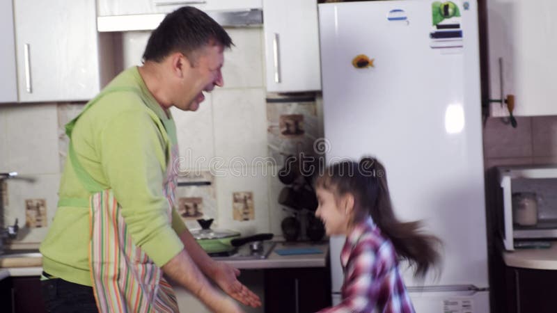 Πατέρας και ευτυχές νέο κορίτσι με το σκοτεινό παιχνίδι τρίχας στην κουζίνα