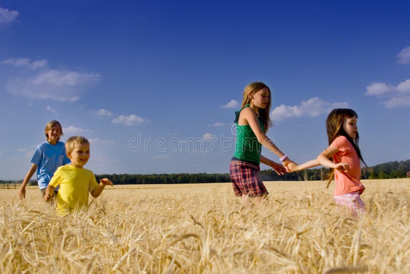 Group of children running through a field of ripe barley under a brilliant blue summer sky. Group of children running through a field of ripe barley under a brilliant blue summer sky.
