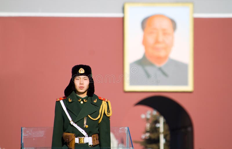 A paramilitary police officer guarding in Tian'anmen square Beijing, China. background is Chairman Mao's portrait. A paramilitary police officer guarding in Tian'anmen square Beijing, China. background is Chairman Mao's portrait