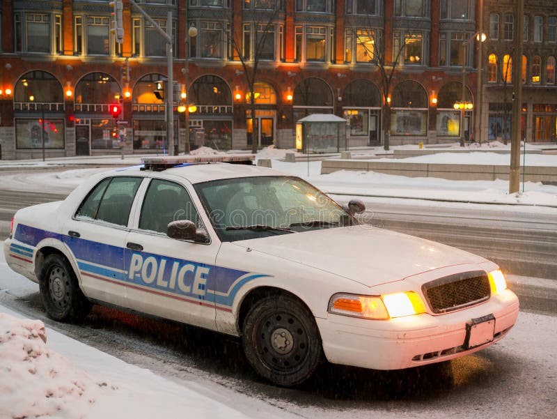 A Police car parked in winter downtown area at night time with snow falling. A Police car parked in winter downtown area at night time with snow falling.