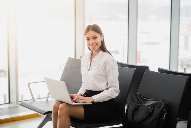 Περιστασιακή γυναίκα που εργάζεται στο lap-top στην αίθουσα αερολιμένων Γυναίκα που περιμένει την πτήση του στο τερματικό αερολιμ στοκ φωτογραφία με δικαίωμα ελεύθερης χρήσης Περιστασιακή γυναίκα που εργάζεται στο lap-top στην αίθουσα αερολιμένων Γυναίκα που περιμένει την πτήση του στο τερματικό αερολιμ στοκ φωτογραφία με δικαίωμα ελεύθερης χρήσης