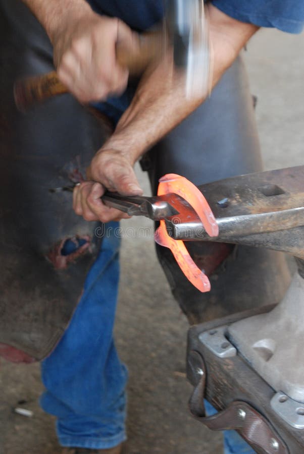 A closeup view of a blacksmith hammering a red hot horseshoe into shape. A closeup view of a blacksmith hammering a red hot horseshoe into shape.