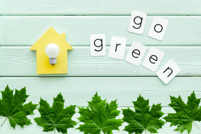 Πηγαίνετε πράσινη έννοια με τα φύλλα σφενδάμου, το σπίτι και το λαμπτήρα τοπ άποψη υποβάθρου μεντών στην πράσινη ξύλινη στοκ φωτογραφία