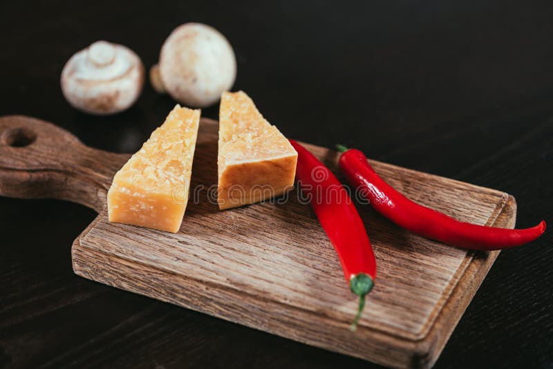 πιπέρια τυριών και τσίλι παρμεζάνας στον ξύλινους τέμνοντες πίνακα και τα μανιτάρια στοκ φωτογραφία πιπέρια τυριών και τσίλι παρμεζάνας στον ξύλινους τέμνοντες πίνακα και τα μανιτάρια στοκ φωτογραφία