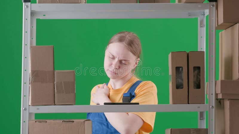 πλαίσιο σε πράσινο φόντο χρωματικής κλίμακας. νεαρή γυναίκα με στολή εργασίας. απεικονίζει έναν αποθηκευτή σε αποθήκη. γυναίκα απόθεμα βίντεο