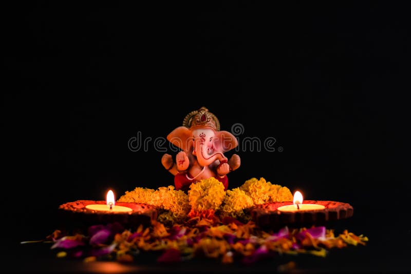 πλατύ άγαλμα του λόρδου ganesha με λουλούδια και δύο λαμπερές λάμπες στο μαύρο φόντο. έννοια θρησκείας στοκ φωτογραφία με δικαίωμα ελεύθερης χρήσης