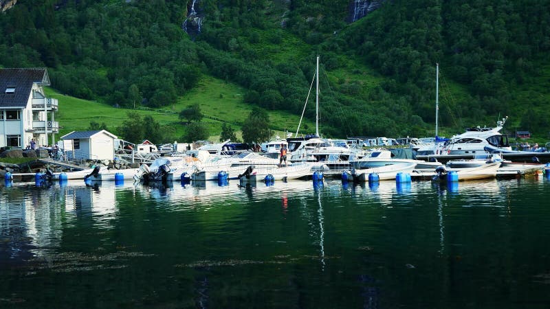 Πολλά σκάφη αναψυχής και οι αντανακλάσεις τους στο φιόρδ νερό στη μαρίνα στο Geirrage της Νορβηγίας κοντά σε ένα απότομο βουνό