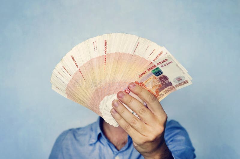 πολλά χρήματα στα χέρια ενός νεαρού επιχειρηματία σε μπλε φόντο Στοίβα τραπεζογραμματίων από ρούβλια Ρωσίας με ονομαστική αξία στοκ εικόνες με δικαίωμα ελεύθερης χρήσης πολλά χρήματα στα χέρια ενός νεαρού επιχειρηματία σε μπλε φόντο Στοίβα τραπεζογραμματίων από ρούβλια Ρωσίας με ονομαστική αξία στοκ εικόνες με δικαίωμα ελεύθερης χρήσης