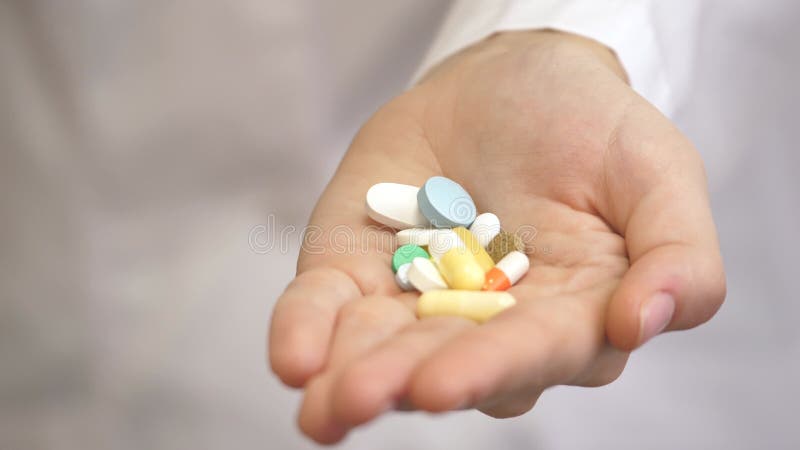 πολλά χρωματιστά χάπια στα γυναικεία χέρια ενός ιατρικού εργαζομένου με λευκό παλτό. η ιατρική της αιώνιας νεολαίας και υγείας απόθεμα βίντεο