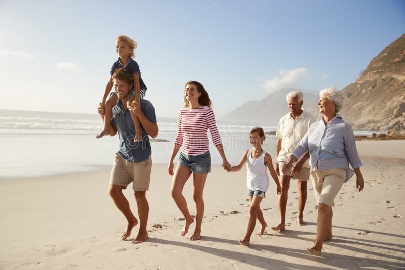 Πολυ οικογένεια παραγωγής στις διακοπές που περπατά κατά μήκος της παραλίας από κοινού