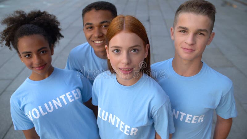 Πολυεθνική ομάδα νεαρών εθελοντών που ψάχνουν φωτογραφική μηχανή, αλτρουιστική δραστηριότητα, βοήθεια