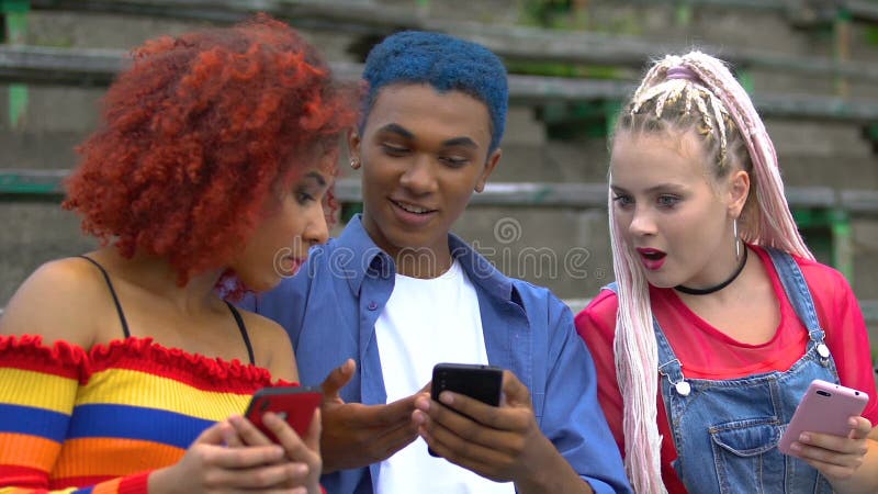 Πολυεθνικοί φίλοι που κάνουν κύλιση στα μέσα κοινωνικής δικτύωσης, με γαλάζια μαλλιά που μοιράζονται τις ειδήσεις των εφαρμογών