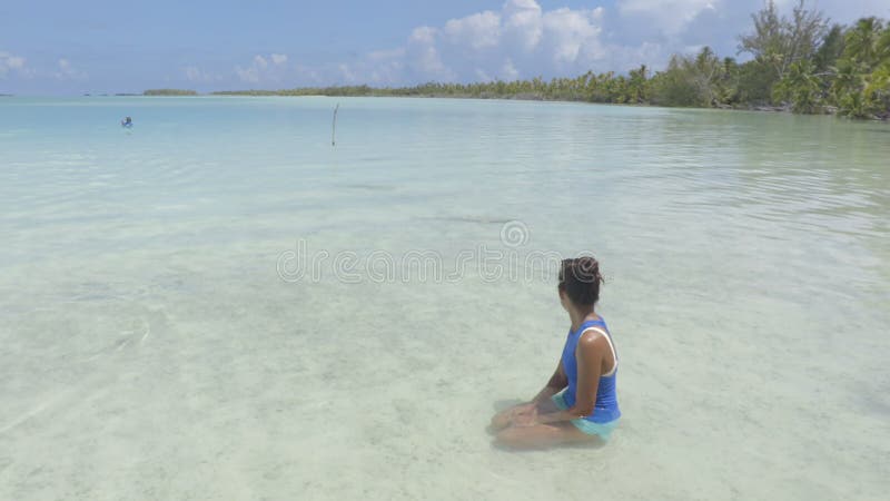 πολυνήσια γυναίκα παραλία που κάθεται δίπλα σε καρχαρίες υφάλων στη λιμνοθάλασσα του κοραλλιού στην ταϊτή