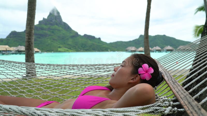 πολυτελές θέρετρο παραλία γυναίκα χαλαρώνει ξαπλωμένη στην αιώρα στη μπόρα μπόρα