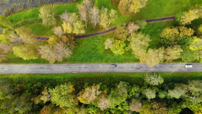 πολύχρωμα φθινοπωρινά δέντρα και δρόμος με αυτοκίνητα την ηλιόλουστη ημέρα. βολή εναερίου drone