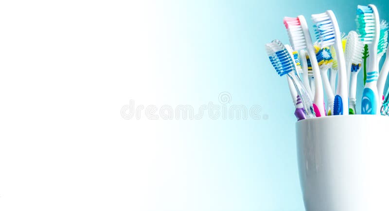 Πολύχρωμες οδοντόβουρτσες σε μια άσπρη κινηματογράφηση σε πρώτο πλάνο κουπών με ένα υπόβαθρο κλίσης από άσπρο στο μπλε με μια απο