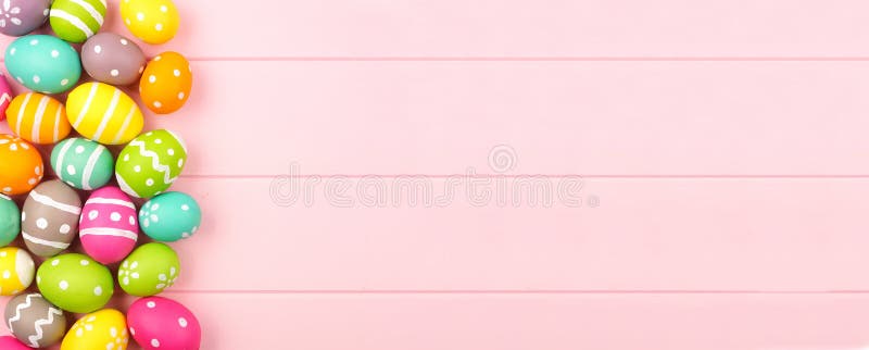 πολύχρωμο πανό πάσχα με πλευρικό περίγραμμα αυγών πάσχα πάνω από ροζ φόντο ξύλου με διάστημα αντιγραφής