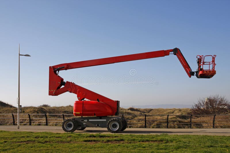 Orange cherry picker, side view against a blue sky. Orange cherry picker, side view against a blue sky