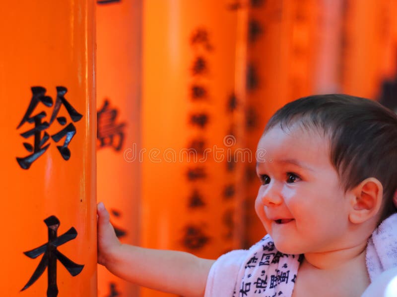 Portrait of a cherful little baby with red colorful toriis of Fushimi Inari Taisha shrine on background, Kyoto, Japan. Portrait of a cherful little baby with red colorful toriis of Fushimi Inari Taisha shrine on background, Kyoto, Japan.