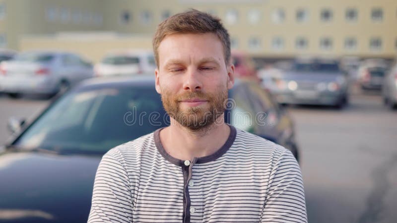 Πορτρέτο ενός επιτυχούς ατόμου που υπερασπίζεται το αυτοκίνητό του στον εξωτερικούς χώρο στάθμευσης και το χαμόγελο