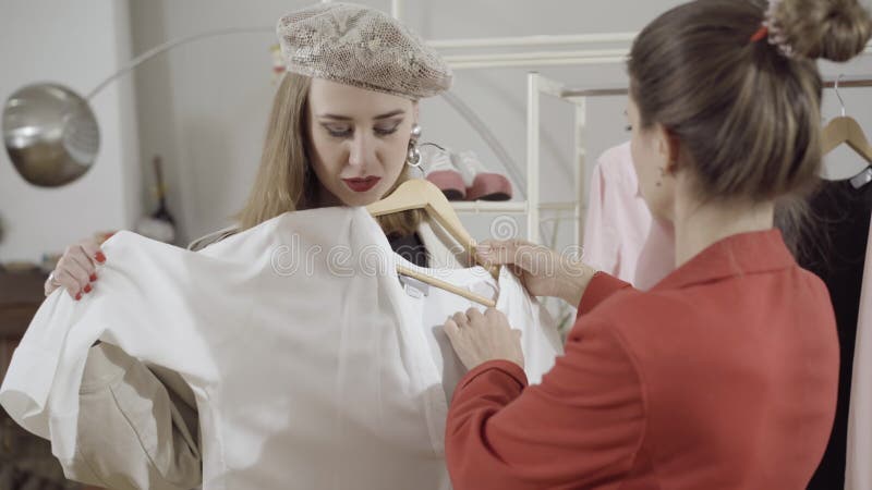 πορτρέτο ενός μοντέρνου πελάτη με αυτοπεποίθηση, επιλέγοντας ρούχα στο ατελιέ με τη βοήθεια σχεδιαστών μόδας ράφτη απόθεμα βίντεο