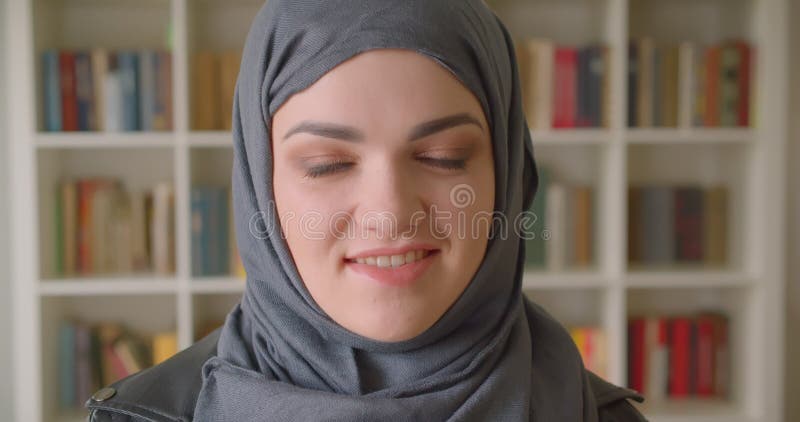 Πορτρέτο κινηματογραφήσεων σε πρώτο πλάνο της νέας ελκυστικής μουσουλμανικής γυναίκας σπουδαστή στο hijab που χαμογελά ευτυχώς να