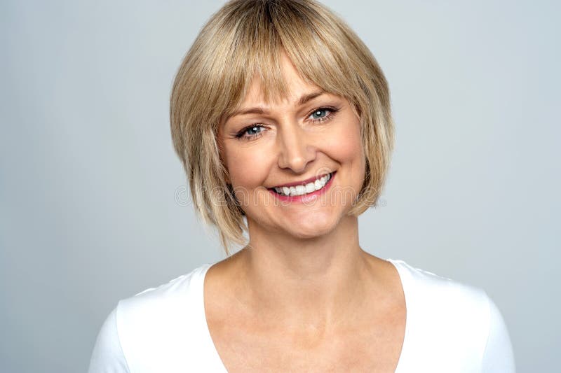 Portrait of a smiling middle aged caucasian woman isolated against grey background. Portrait of a smiling middle aged caucasian woman isolated against grey background.