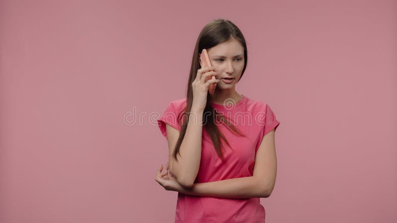 πορτρέτο μοντέλου μόδας μιλάει στο smartphone της. νεαρή καστανή γυναίκα με μακριά μαλλιά με ροζ μπλουζάκι απόθεμα βίντεο