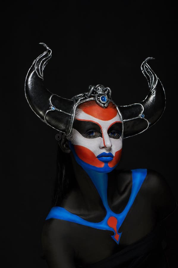 Mystery portrait of female faun with blue eyes, body art and silver snakes on black horns. Mystery portrait of female faun with blue eyes, body art and silver snakes on black horns