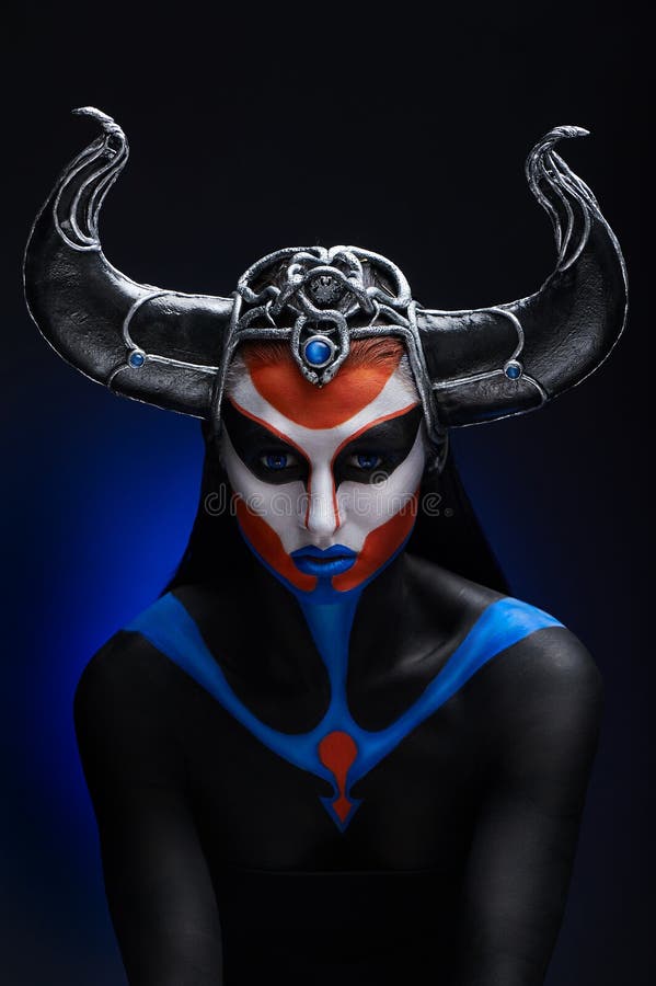 Mystery portrait of female faun with blue eyes, body art and silver snakes on black horns. Mystery portrait of female faun with blue eyes, body art and silver snakes on black horns