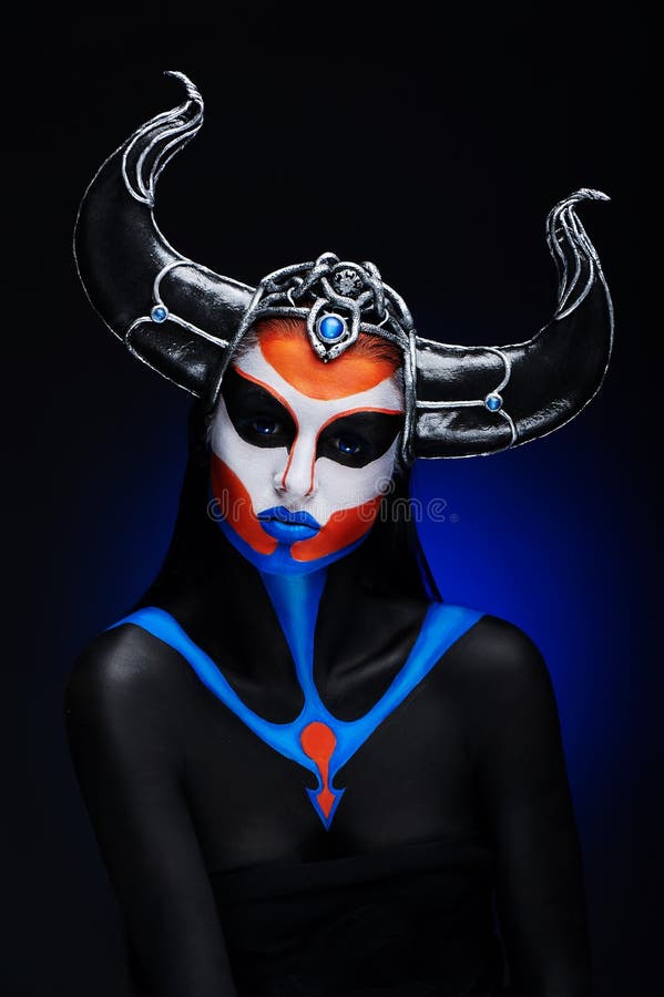 Mystery portrait of female faun with blue eyes, body art and silver snakes on black horns. Mystery portrait of female faun with blue eyes, body art and silver snakes on black horns