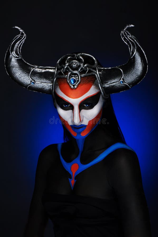 Mystery portrait of female faun with blue eyes, body art and silver snakes on black horns. Mystery portrait of female faun with blue eyes, body art and silver snakes on black horns