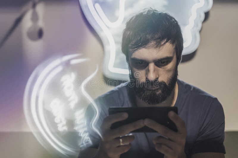 Πορτρέτο της νέας γενειοφόρου συνεδρίασης ατόμων στο κινητές τηλέφωνο χεριών καφέδων και εκμετάλλευσης και την οθόνη δακτυλογράφη στοκ εικόνα
