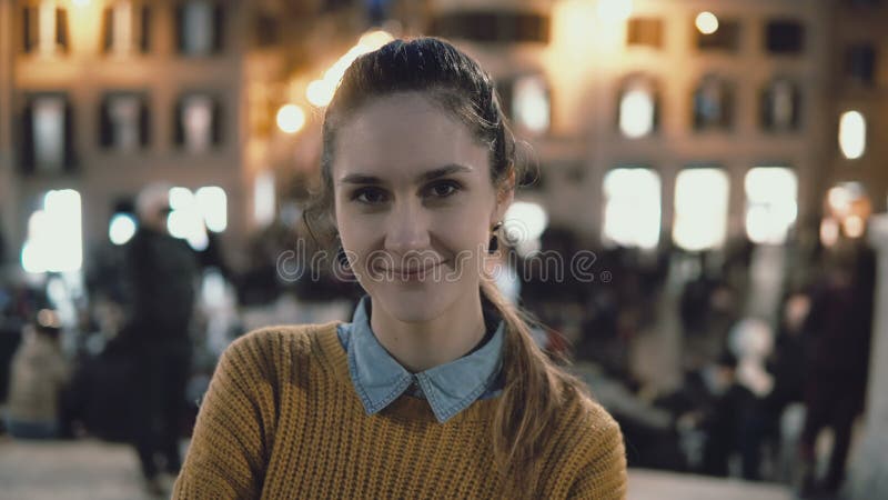 Πορτρέτο της νέας όμορφης στάσης γυναικών στο κέντρο της πόλης το βράδυ Το κορίτσι σπουδαστών εξετάζει τη κάμερα, χαμόγελο στοκ φωτογραφία Πορτρέτο της νέας όμορφης στάσης γυναικών στο κέντρο της πόλης το βράδυ Το κορίτσι σπουδαστών εξετάζει τη κάμερα, χαμόγελο στοκ φωτογραφία