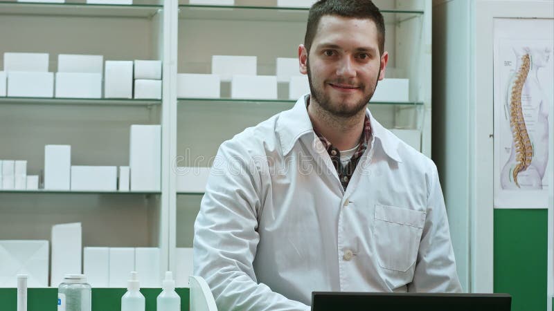 Πορτρέτο του νέου αρσενικού φαρμακοποιού που εξετάζει τη κάμερα και το χαμόγελο
