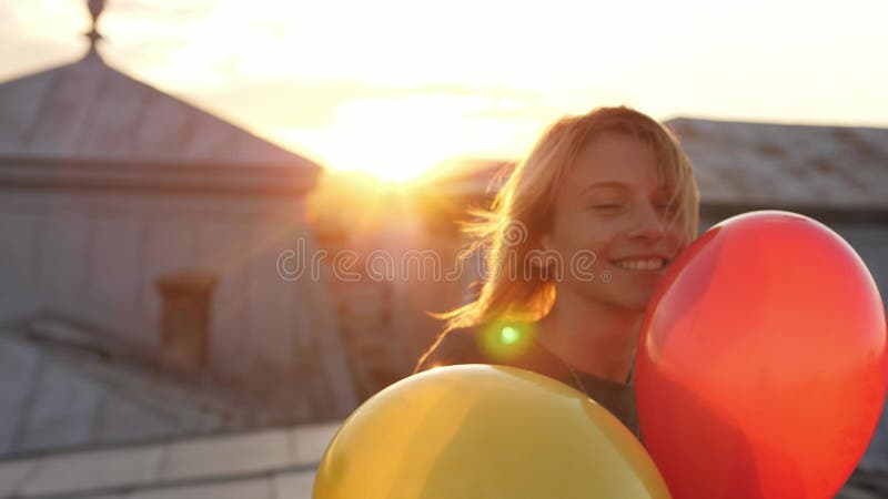 Πορτρέτο του νέου κοριτσιού που περπατά στην εκμετάλλευση καμερών στα χέρια μερικά μπαλόνια